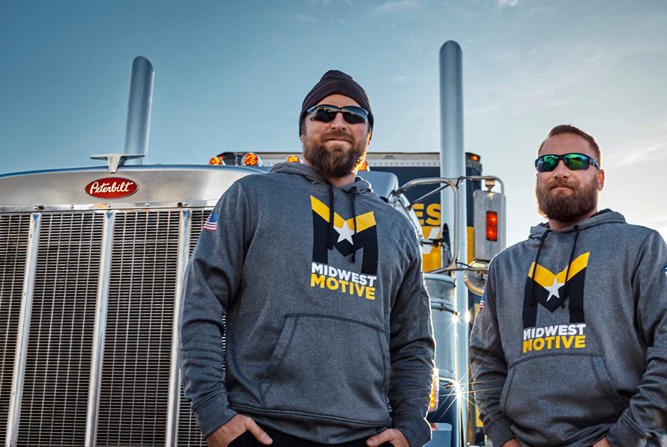 Midwest Motive drivers in front of a semi-truck.