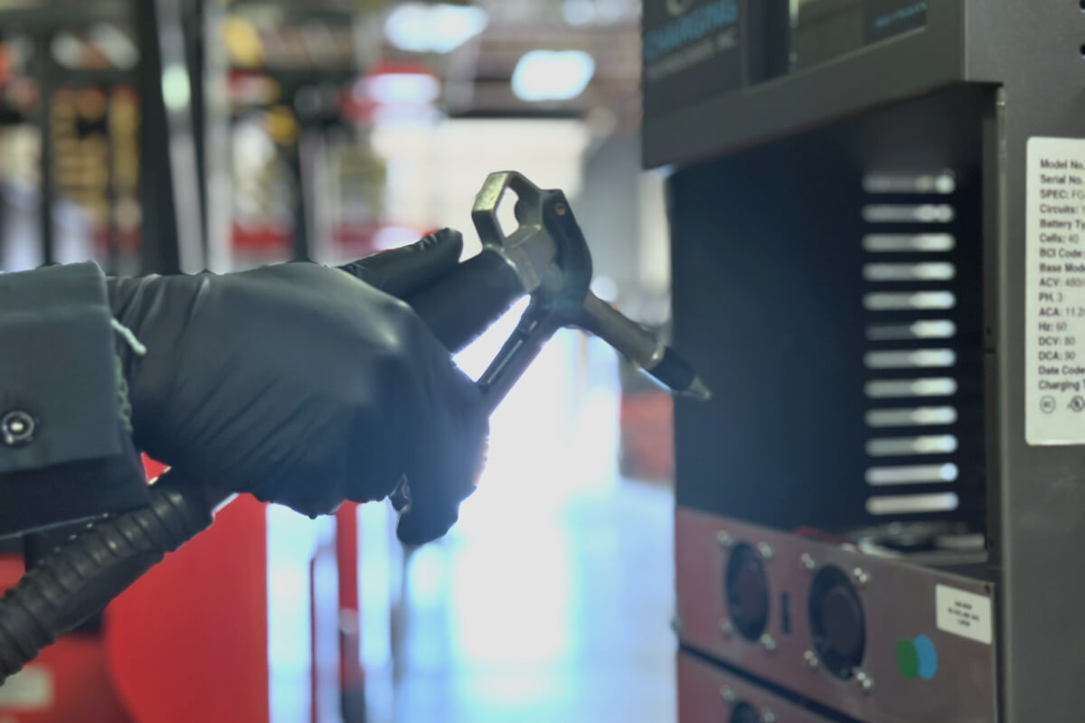 Workers performing dust and debris removal on an industrial battery charger